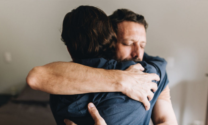 Two men embrace.