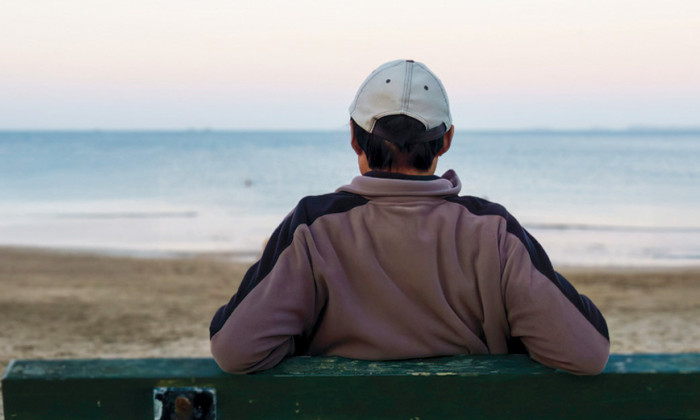 Man sitting on a bench looking out to sea.