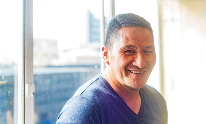 Man smiling in the sunlight by a window